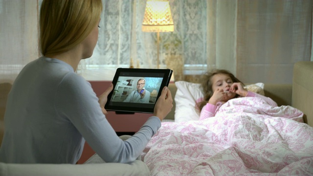 妈妈带着一个生病的女儿在家里通过视频聊天得到医生的咨询。视频素材
