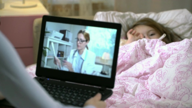 妈妈带着一个生病的女儿在家里通过视频聊天得到医生的咨询。视频素材
