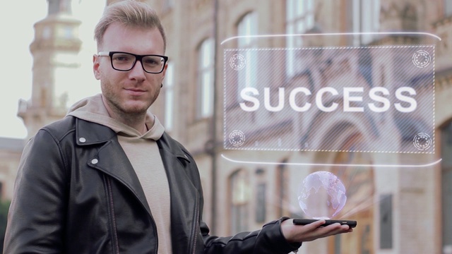 聪明的年轻人戴着眼镜展示了一个概念全息图的成功视频素材