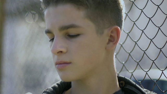 少年倚在铁栅栏上，想着自己的未来，少年犯聚居地视频素材