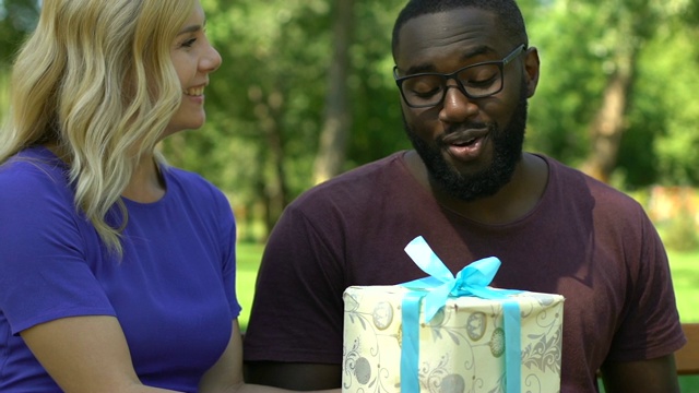 一位女士在公园休息时给非裔美国人男友圣诞礼物视频素材