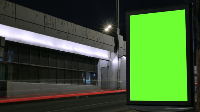 时间流逝。有绿色屏幕的广告牌，位于繁忙的街道上。汽车在晚上行驶。视频素材