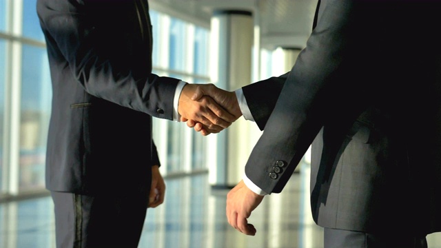 这两个商务人士在办公室大厅里握手。慢动作视频下载