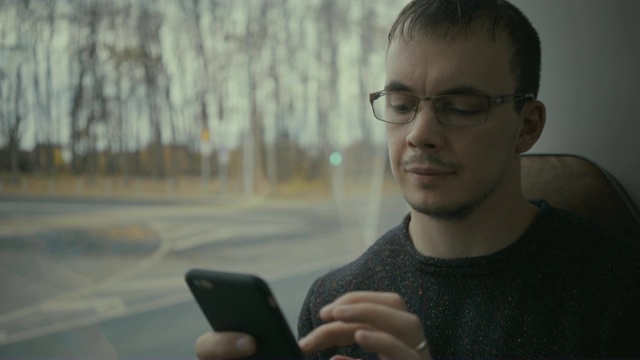 一名年轻人在乘坐公交车时使用智能手机视频素材