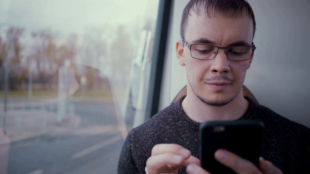 一名年轻人在乘坐公交车时使用智能手机视频素材