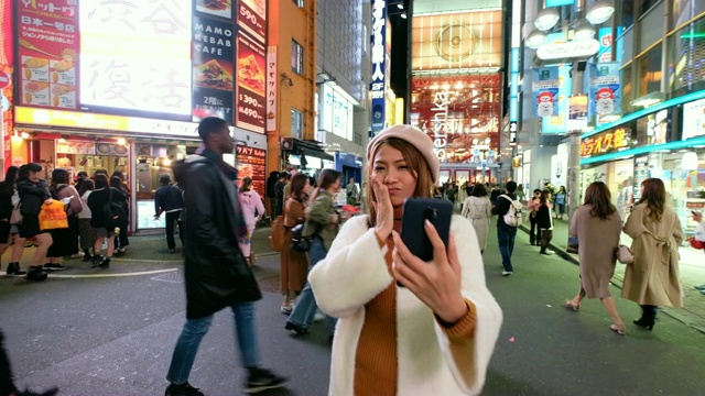 4K移动拍摄:一名亚洲女性在涉谷步行街用手机自拍，背景是许多广告牌。东京涩谷具有里程碑意义的视频下载