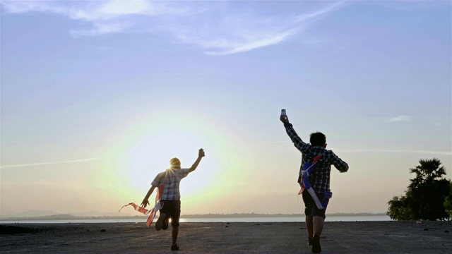 快乐的两个孩子男孩带着风筝在马路上奔跑，在夏日阳光明媚的大自然中。慢动作视频素材