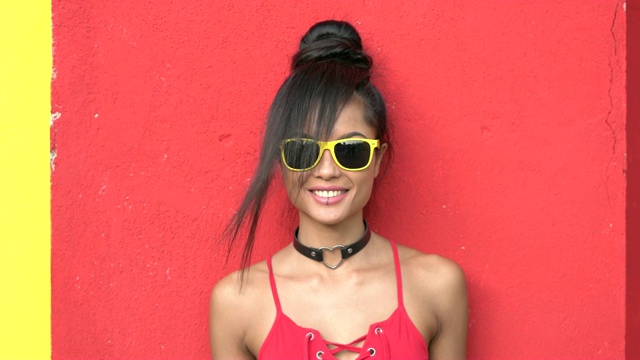 微笑的年轻女子站在红墙前视频素材