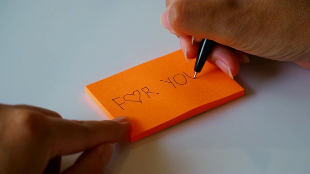 把单词“for you”写在橙色的便条纸或记事本上。4 k运动镜头视频下载