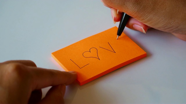 把“爱”字写在橙色的便条纸或记事本上视频下载