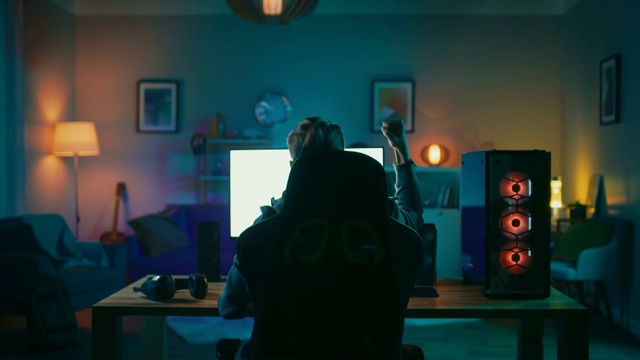 Back Shot of a Gamer Playing and Winning in First-Person Shooter Online Video Game on His Powerful Personal Computer.一个玩家在他的强大的个人电脑上玩第一人称射击在线视频游戏并获胜。房间和电脑都有彩色霓虹灯。温馨的家庭之夜。视频素材