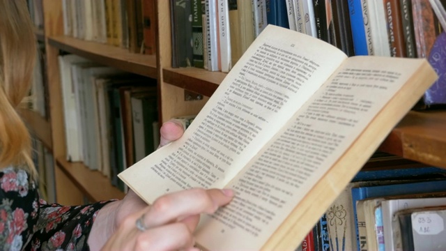 手里拿着书的女孩在图书馆的书架上阅读视频素材