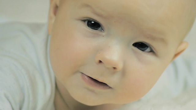 一个6个月大的婴儿说话和看着慢镜头的特写。视频素材