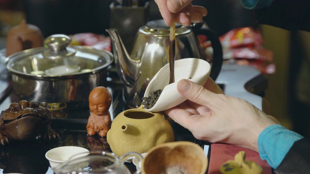 茶道。师傅用木勺把绿茶舀进茶壶里视频素材