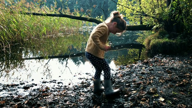 小女孩在湖边泥泞的水坑里玩耍视频素材