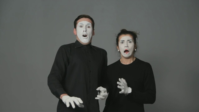 恐惧的哑剧艺术家男人和女人在灰色的背景。视频素材