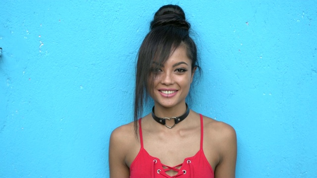 微笑的亚洲女人站在蓝色墙壁前视频素材