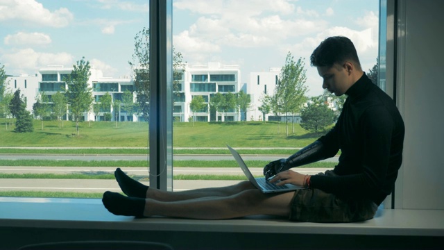 男性少年用仿生手臂在笔记本电脑上打字。未来的半机械人概念。视频下载