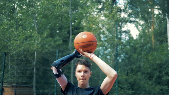 一个少年用仿生机器人的手扔篮球的慢动作视频下载