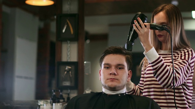 沙龙里的男性发型。理发师在理发店里吹头发。理发师用吹风机做发型。完成美容。理发店里的吹风机男视频素材