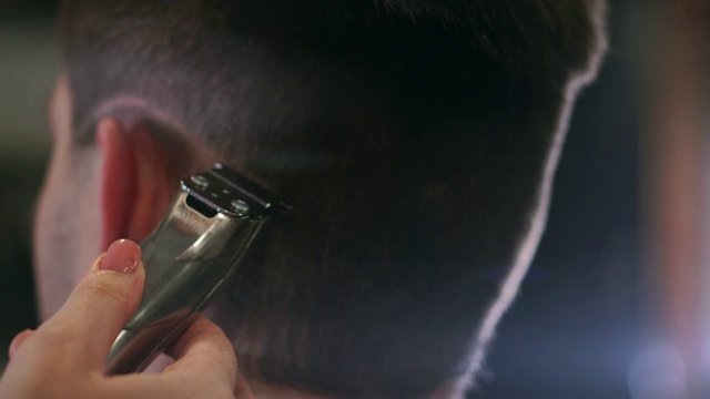 美容学校的理发师用电动剃须刀为男士理发。女理发师在理发店里用理发器为男士理发视频下载