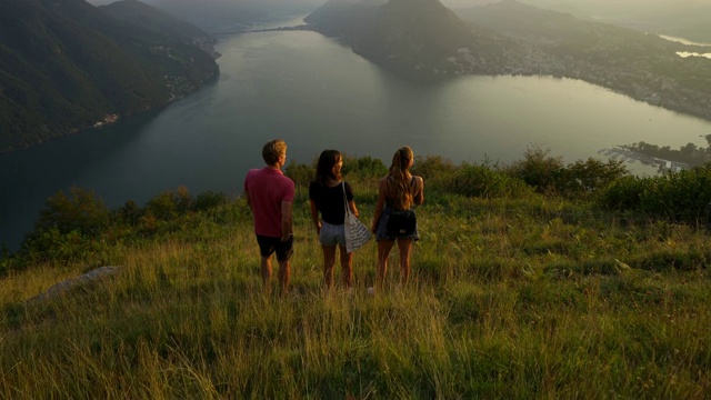 两个女人和一个男人望着日落时的湖景视频素材