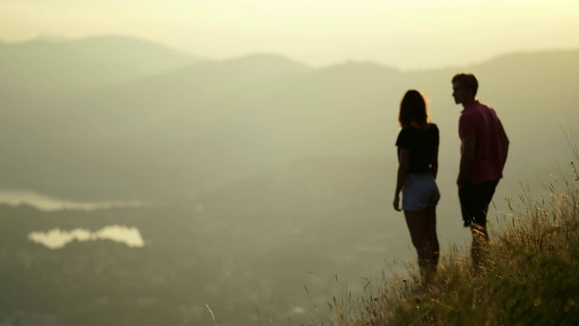年轻的夫妇看日落在山上俯瞰湖视频素材