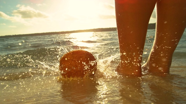 慢镜头:一名不知名的女游客站在海里，把一个椰子扔进水里。视频素材