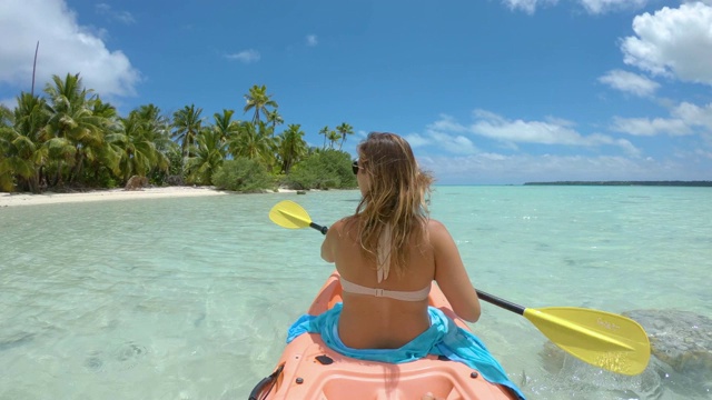 慢镜头:游客女孩划着皮划艇驶向美丽的白色沙滩。视频下载