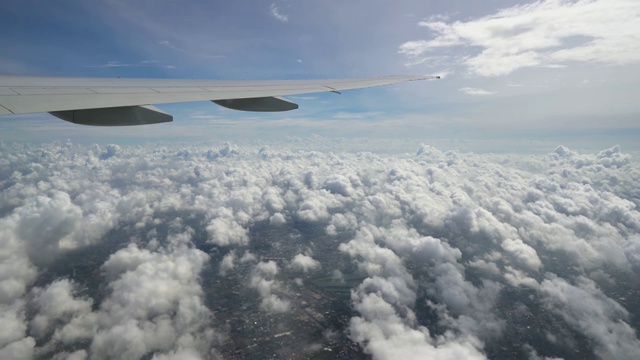 飞机在蓝天白云之上飞行，飞机的机翼靠近视频下载