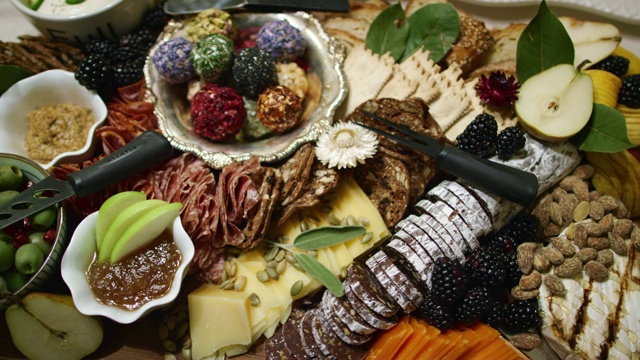 在室内庆祝/派对的桌子上，镜头围绕着开胃肉/奶酪板和各种水果，酱汁和装饰视频下载