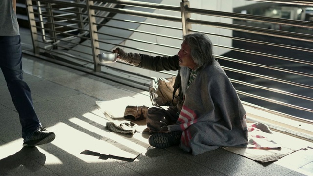 在人行道上，无家可归的人拿着乞讨的碗。视频下载