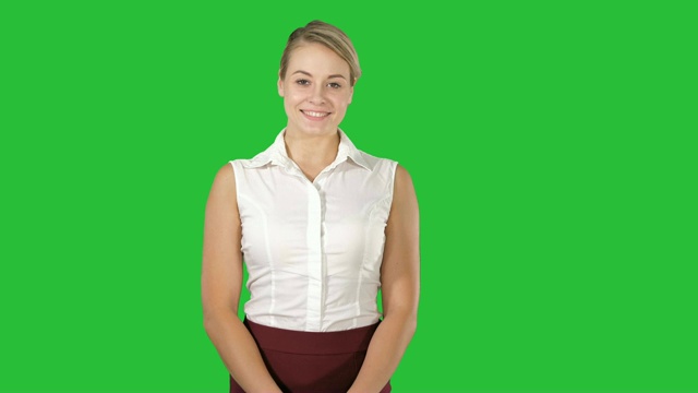 一个年轻美丽的女孩的肖像站在一个绿色屏幕上看着害羞，色度键视频下载
