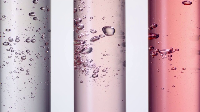 把水倒进三个红色和粉色的科学试管中，产生气泡视频素材