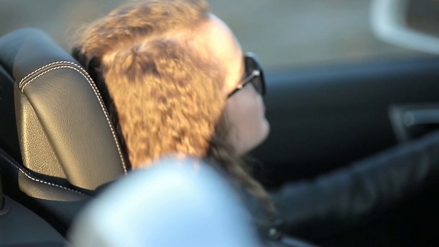 美丽性感的女孩长头发，皮夹克和皮裤，戴着墨镜坐在一辆敞篷车视频素材