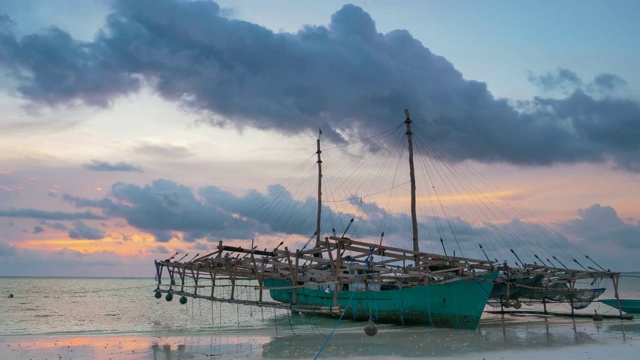 日落时分的热带海滩和大海。黄昏时绚丽多彩的天空。印尼摩鹿加岛基岛的传统渔船。视频素材