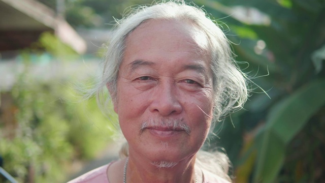 60年代男人的肖像，微笑的亚洲老人。老人看着相机。视频素材