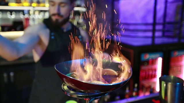 蓄着胡子的酒保把肉桂和橙子倒在煤气灶上的平底锅里。视频下载