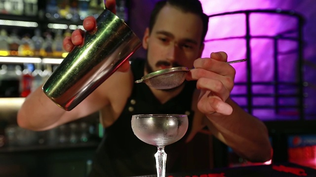 胡子男侍者把准备好的鸡尾酒倒进玻璃杯。视频下载