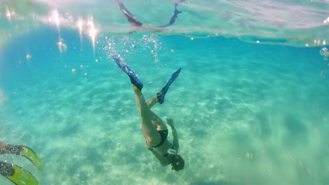 女士用脚蹼潜入阳光明媚的蓝绿色海洋视频素材