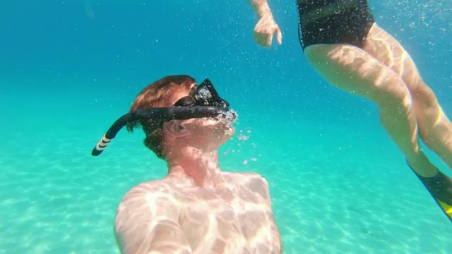 克罗地亚Peljesac，一对夫妇在阳光明媚的蓝色海洋中浮潜视频素材