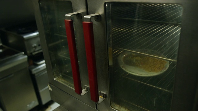 三十多岁的西班牙男厨师在一家墨西哥餐厅的商用烤箱里放了一盘食物视频素材
