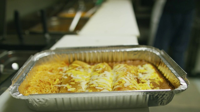 在墨西哥餐厅的商业厨房里，一个人将打开的玉米粉蒸肉放入一个装有奶酪和米饭的金属烤盘里视频下载