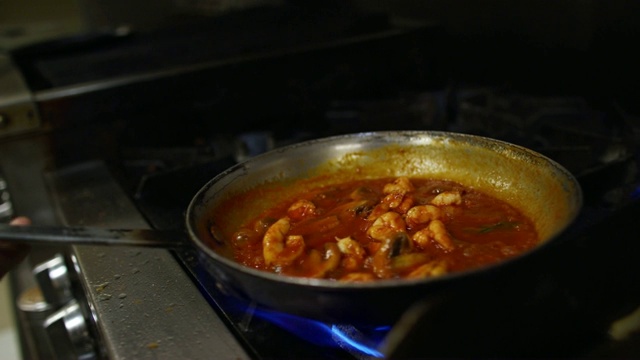 一位年轻的西班牙男性厨师用平底锅煮虾和红酱视频素材
