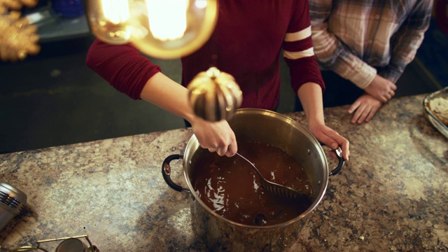 头顶拍摄的两个女孩搅拌一大锅热巧克力在一个厨房的柜台上视频下载