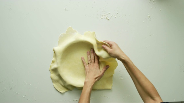 头顶上一个女人的手形成一个扁平的面团在馅饼盘里准备填充的镜头视频下载