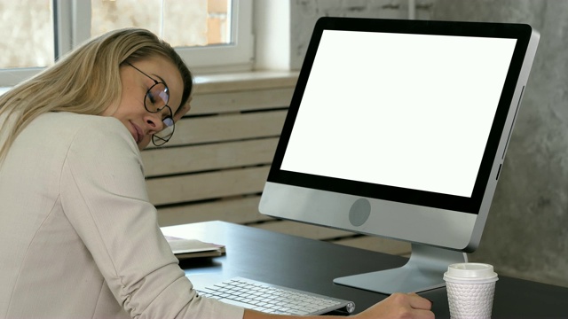 疲惫的女商人坐在显示器前的办公桌前。白色显示视频素材
