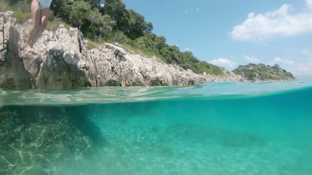 克罗地亚佩列沙茨，男子戴着可穿戴相机拍摄妻子潜入阳光明媚的蓝绿色海洋视频素材