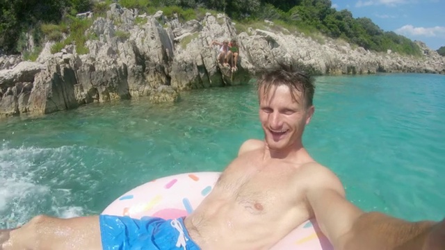 克罗地亚Peljesac，可穿戴相机拍摄充气筏子上的男子在阳光明媚的海洋上溅起水花，踢着脚视频素材