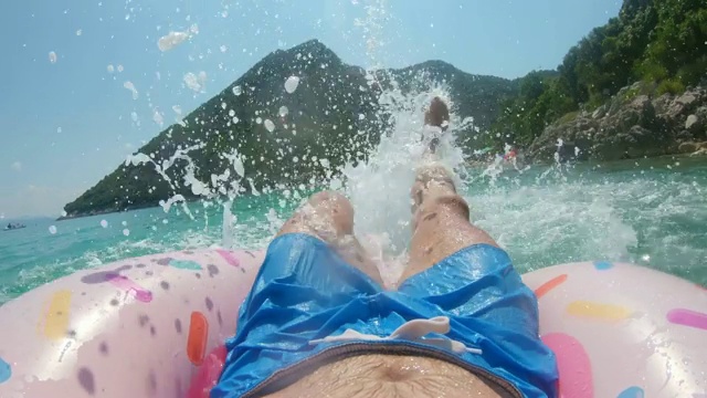 个人观点:在阳光明媚的海洋上，充气圈上溅起水花，踢腿，克罗地亚Peljesac视频素材
